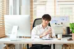 年轻的现代商人白色衬衫穿手腕看坐着明亮的办公室室内