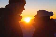 一边视图的轮廓夫妇徒步旅行者站美丽的日出日落前山清晰的天空背景男人。女人