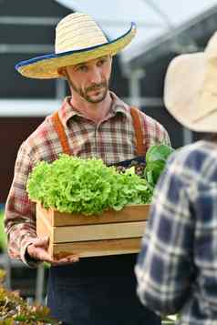 肖像微笑男人。农民给木箱完整的新鲜的有机蔬菜客户