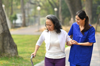 年轻的有<strong>爱心</strong>的女护士帮<strong>助</strong>高级女人走公园援<strong>助</strong>康复概念