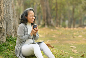 优雅的上了年纪的女人喝咖啡享受户外休闲活动温暖的一天真实的高级退休生活概念