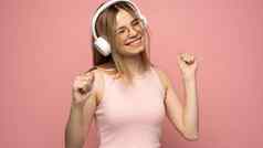 金发女郎女人眼镜粉红色的t恤听音乐耳机少年女孩跳舞粉红色的背景