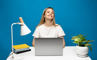 年轻的成功的快乐员工业务女人休闲白色衬衫坐工作办公室桌子上移动PC电脑工作空间区域赢家手势孤立的蓝色的背景工作室
