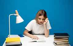 累了年轻的学生女人白色休闲衣服坐着表格阅读书图书馆大学大学坐着阅读蓝色的背景研究
