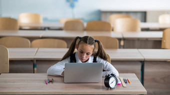 高加索人女孩坐在桌子上学校研究移动PC报警时<strong>钟表</strong>格