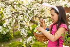 可爱的孩子女孩穿兔子耳朵复活节一天女孩狩猎复活节鸡蛋草坪上房子女孩持有篮子画鸡蛋
