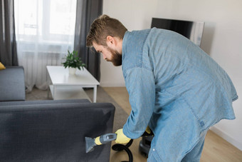 男人。保护橡胶手套清洁沙发专业提取方法洗真空更清洁的早期春天常规的清理商业清洁公司概念