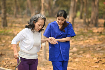 图像有<strong>爱心</strong>的女照顾者帮<strong>助</strong>高级女人走公园援<strong>助</strong>康复概念