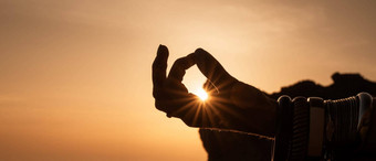 横幅年轻的女人的手手镯实践瑜伽海滩日落手指连接太阳照概念健康的生活方式和谐