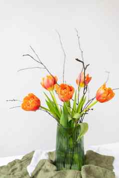 美丽的春天花束绿色花瓶站表格亚麻桌布橙色牡丹郁金香母亲的一天3月情人节一天
