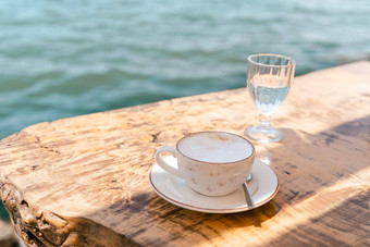 卡布奇诺咖啡拿铁咖啡杯杯子玻璃<strong>水站</strong>木表格咖啡馆风景海山背景复制空白空间