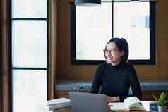 肖像十几岁的亚洲女人穿眼镜电脑移动PC耳机移动PC研究在线视频会议木图书馆表格