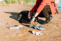 年轻的女志愿者满意挑选垃圾塑料瓶咖啡杯清洁海滩海女人收集垃圾环境生态污染概念地球一天