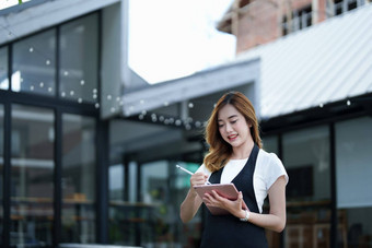 开始开放小业务年轻的亚洲女人显示微笑脸持有平板电脑围裙站前面咖啡商店酒吧计数器业务老板餐厅咖啡馆概念