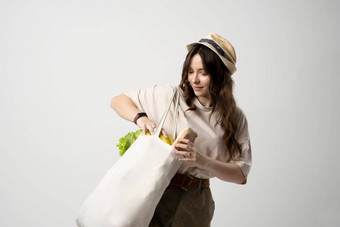 微笑年轻的女人米色t恤哈勃太空望远镜网生态袋完整的蔬菜白色工作室背景可持续发展的生活方式生态友好的概念浪费