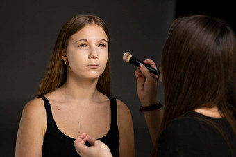 关闭脸美丽的年轻的女人粉脸颊刷专业化妆艺术家