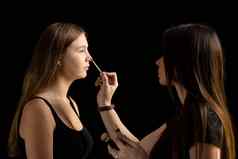 化妆艺术家应用液体色调基金会脸女人使房间专业化妆艺术家工作刷模型脸