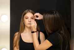 化妆艺术家应用液体色调基金会脸女人使房间
