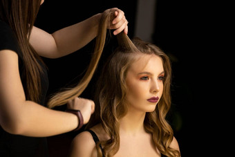 专业头发设计师准备女人使卷发发型美沙龙长光棕色（的）自然头发