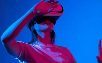 女玩家进入游戏穿虚拟现实护目镜霓虹灯光年轻的女人经历<strong>身临其境</strong>的技术工作室