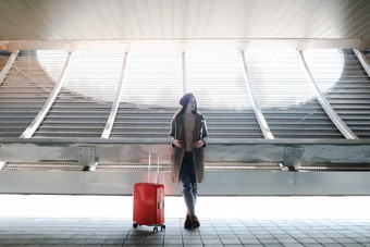 年轻的女人旅游红色的旅行手提箱未来主义的外观现代体系结构旅行者<strong>走红</strong>色的手提箱现代机场概念城市运输旅行