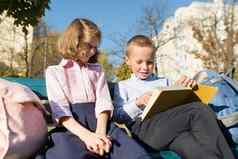 男孩女孩小学生阅读书坐着板凳上孩子们背包