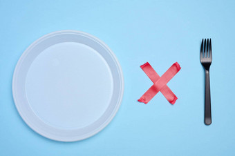 空白色塑料板塑料叉附加红色的胶粘剂磁带蓝色的背景概念拒绝塑料餐具回收材料浪费