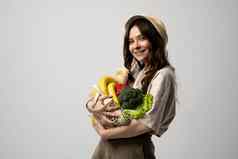 浪费概念浅黑肤色的女人女人米色t恤他网袋完整的新鲜的蔬菜水果超市可持续发展的生活方式塑料