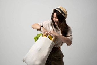 女人持有纺织杂货店袋蔬菜浪费概念package-free食物购物生态友好的自然袋有机水果蔬菜