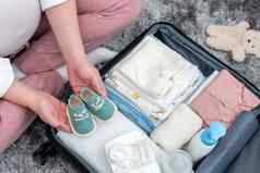 怀孕了女人持有婴儿鞋子包装孕妇医院袋妈妈。怀孕