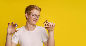 年轻的男人。持有首页建筑模型模型关键黄色的背景展示成就首页所有权成功真正的房地产市场