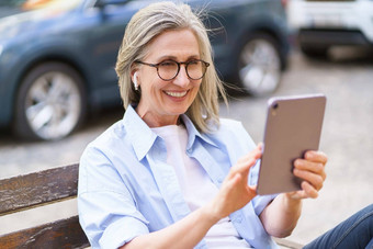 快乐自信成熟的女人微笑持有平板电脑采取调用忙城市城市场景现代技术传达感觉连接方便女人的积极的能源独立的精神激励成功活力