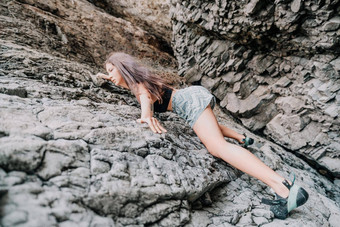 体育女人攀爬岩石年轻的女人苗条的适合身体攀爬火山玄武岩洞穴美丽的海视图运动员女孩火车自然女人克服了困难攀爬路线