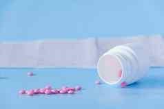 大一些粉红色的药片倒白色Jar心电图心蓝色的背景概念健康的生活方式及时的医疗检查