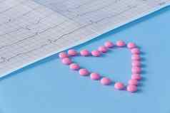 大一些粉红色的药片谎言形式心心电图蓝色的背景概念健康的生活方式及时的医疗检查
