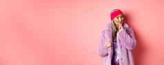 时尚购物概念时尚的亚洲夫人紫色的人造革外套感兴趣感兴趣促销活动微笑思考粉红色的背景