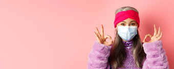 科维德病毒时尚概念特写镜头时尚亚洲<strong>高级</strong>女人脸面具显示迹象快乐粉红色的背景