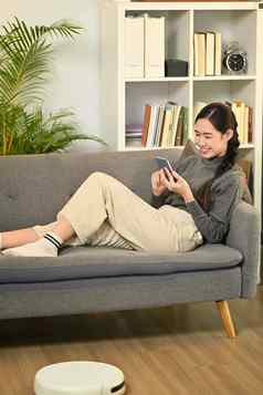 快乐年轻的女人放松沙发上聊天在线移动电话人技术生活方式概念