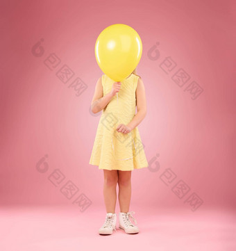 气球封面脸女孩孩子工作室孤立的粉红色的背景模型孩子们生日聚会，派对庆祝活动事件年轻的害羞的孩子隐藏黄色的空气气球充气