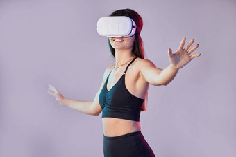 虚拟现实健身元宇宙女人工作室孤立的紫色的背景玩家微笑快乐女运动员未来主义的耳机游戏的<strong>电子竞技</strong>幻想模拟