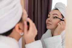 女人适用于黑色的睫毛膏睫毛化妆刷年轻的美丽的女人应用睫毛膏化妆眼睛浴室