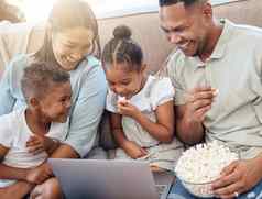 电影爆米花家庭沙发移动PC看流媒体笑喜剧爱黑色的家庭妈妈爸爸孩子们吃零食成键享受在线娱乐