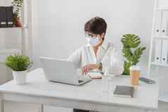 有吸引力的成熟的业务女人工作移动PC工作站医疗脸面具经理办公室流感大流行科维德概念