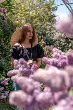 肖像年轻的女人长头发在户外盛开的淡紫色花园
