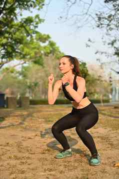 美丽的运动女人运动服装蹲锻炼在户外健身体育运动健康的生活方式概念