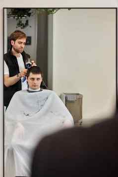 专业理发师工作男人。客户端头发干燥机