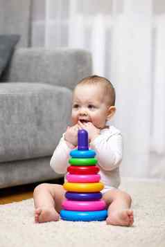 可爱的婴儿女孩玩色彩斑斓的玩具金字塔