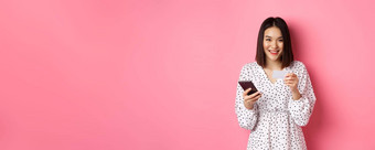 美丽的亚洲女人输入信贷卡信息移动电话应用程序购物在线支付订单智能手机站粉红色的背景