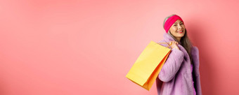 时尚的亚洲<strong>高级</strong>女人购物携带纸袋肩膀微笑快乐相机站粉红色的背景