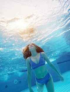 青少年女孩游泳水蓝色的池